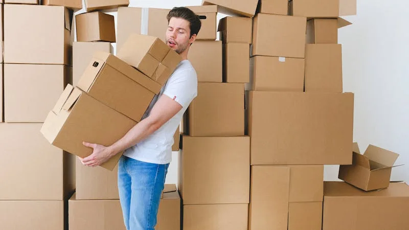 Person carrying a stack of free cardboard moving boxes