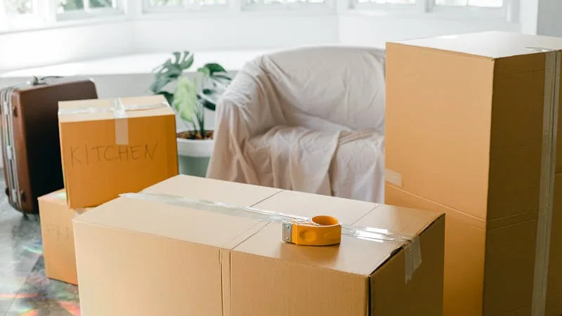 Moving boxes labeled KITCHEN with a tape gun on top